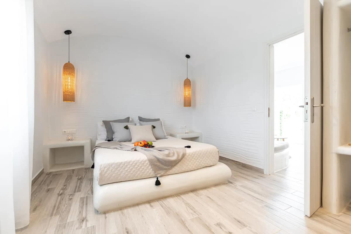 A modern bedroom with a bed, bedside tables, and pendant lights.