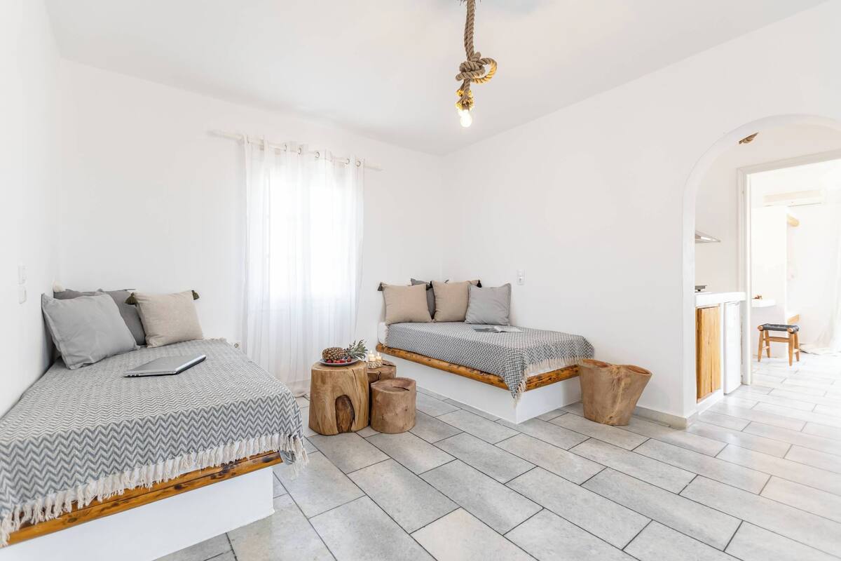 A modern bedroom with two beds, a wooden bench, and a small table with decorative items.