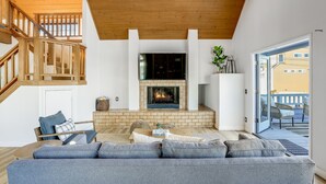Una sala de estar moderna con chimenea, una escalera y vistas al exterior.