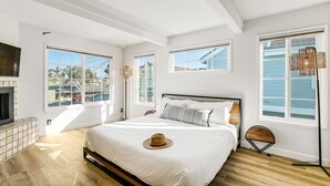 Un dormitorio con una cama grande, una chimenea y varias ventanas con vistas al exterior.