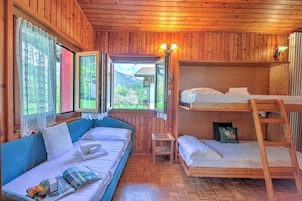 Una baita in legno con un letto a castello, un divano e un tavolino.