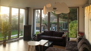 A spacious living room with a large window, a sofa, a coffee table, and a hanging light fixture.
