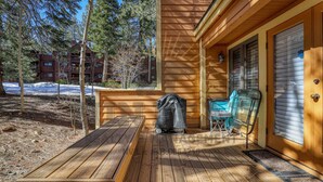 A wooden deck with a barbecue grill, a folding chair, and a covered table. - An unforgettable escape to Lake Tahoe (MC250) (Incline Village)