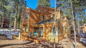 A two-story log cabin with a front porch, surrounded by tall pine trees. - An unforgettable escape to Lake Tahoe (MC250) (Incline Village)