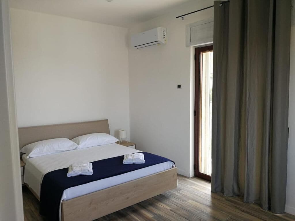 A bedroom with a wooden bed, white pillows, a dark blue bedspread, and a white blanket folded on the bed.