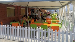An outdoor seating area with tables and chairs under a white canopy, adjacent to a building with windows and a white picket fence. - b&b Crispino (Belvedere Marittimo)