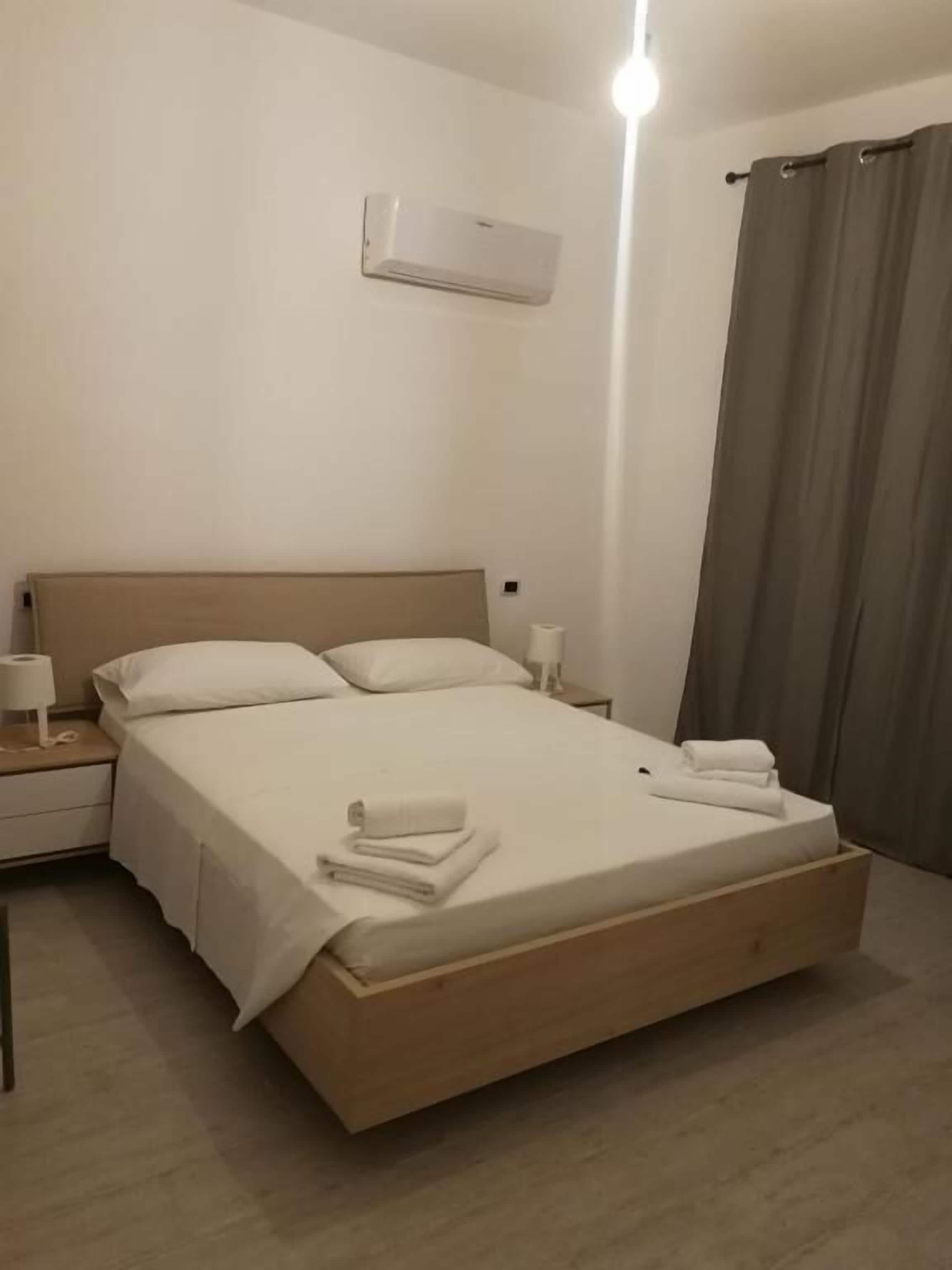 A neatly made bed with white linens, a wooden headboard, and two bedside tables with lamps.
