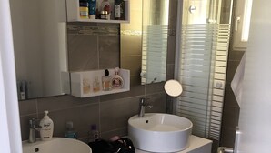 Et moderne badeværelse med to håndvaske, et spejl og en brusekabine.