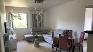 En moderne stue med en modulsofa, et glasbord og et spiseområde med pink stole.