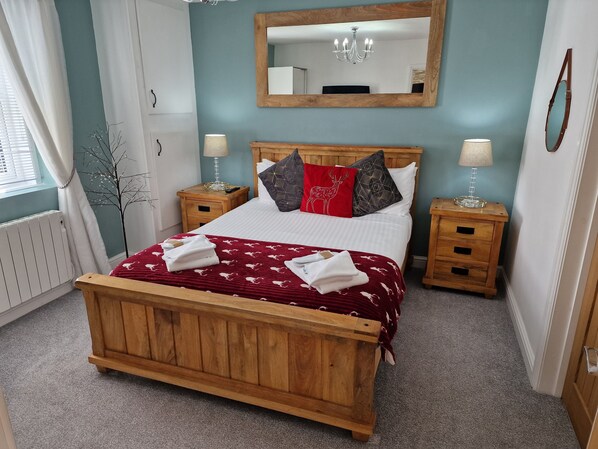 Une chambre à coucher avec un lit en bois, deux tables de chevet, un miroir et un radiateur.
