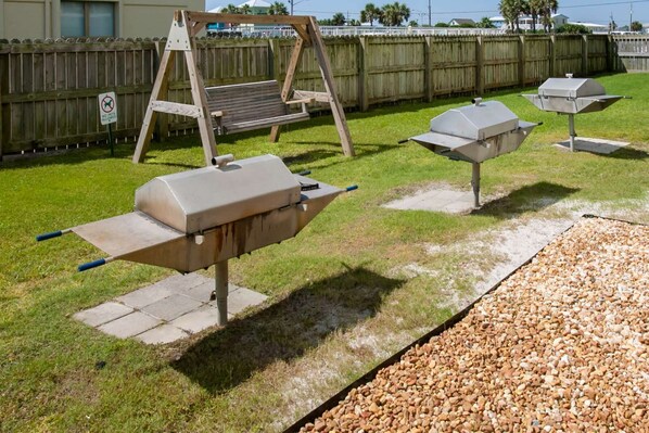 A backyard with a swing set, a barbecue grill, and a wooden fence. - Halloween Sale! Amazing Gulf View~2BR/2B w/Pool (Gulf Shores)