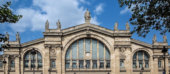 A grand building with classical architecture, featuring statues, large arched windows, and the inscription "NORD".