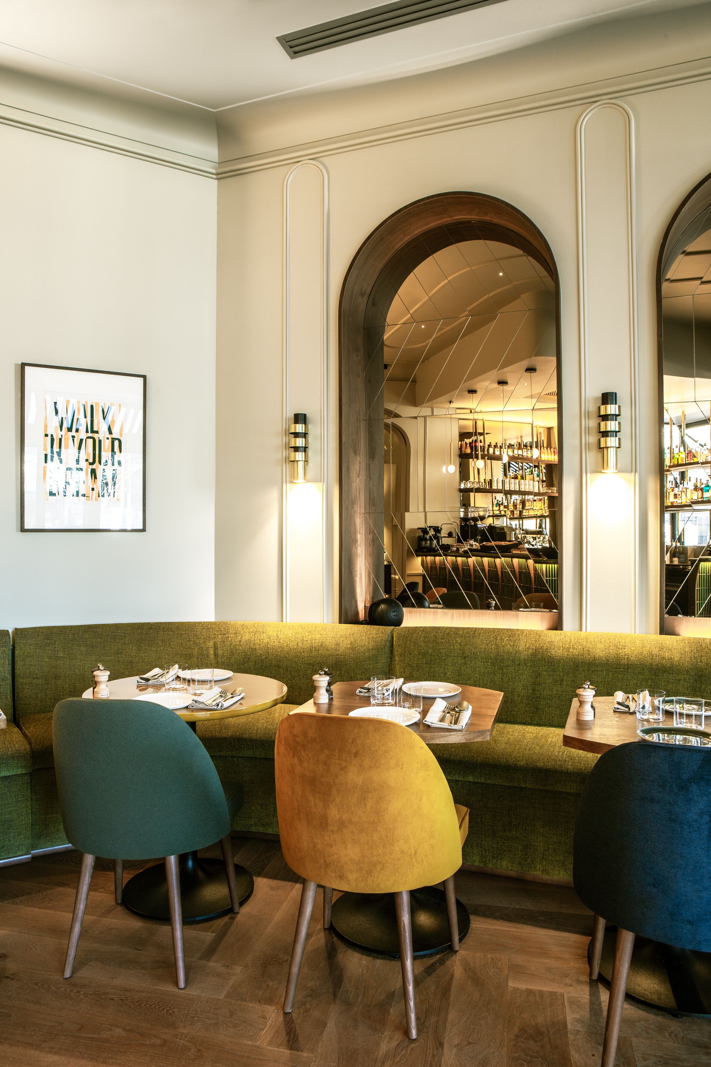 A restaurant with a green cushioned bench seating area, wooden tables, and chairs.