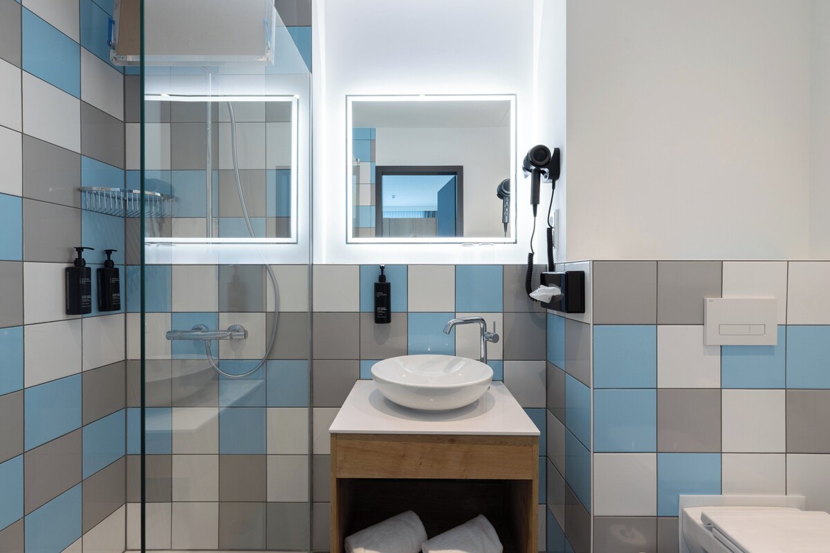 A modern bathroom with a glass-enclosed shower, a white sink, and a mirror above it.