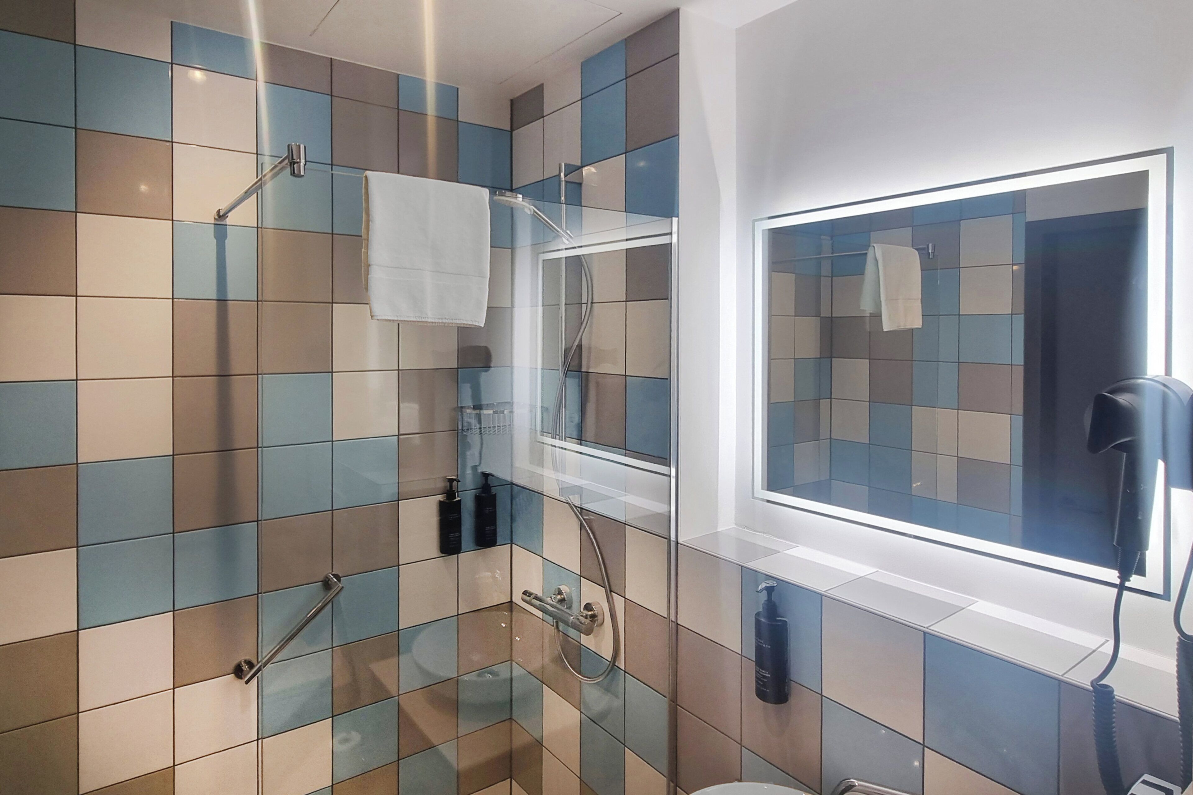 Un baño con cabina de ducha de vidrio, inodoro y lavamanos.