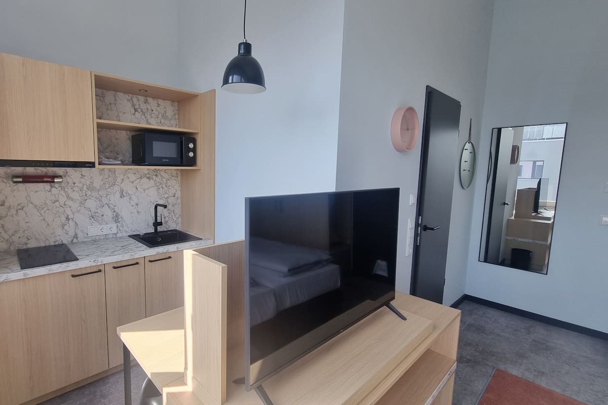 Ein kompakter Wohnbereich mit Küchenzeile, Flachbildfernseher und Spiegel.