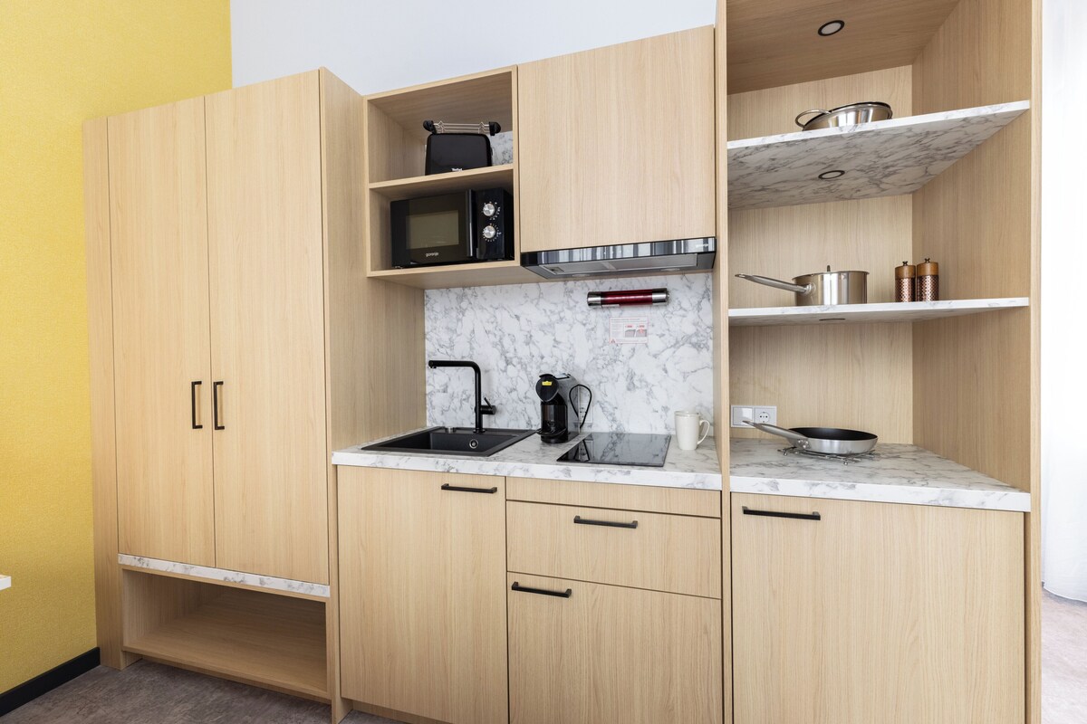 Een kleine keuken met een spoelbak, magnetron en fornuis.