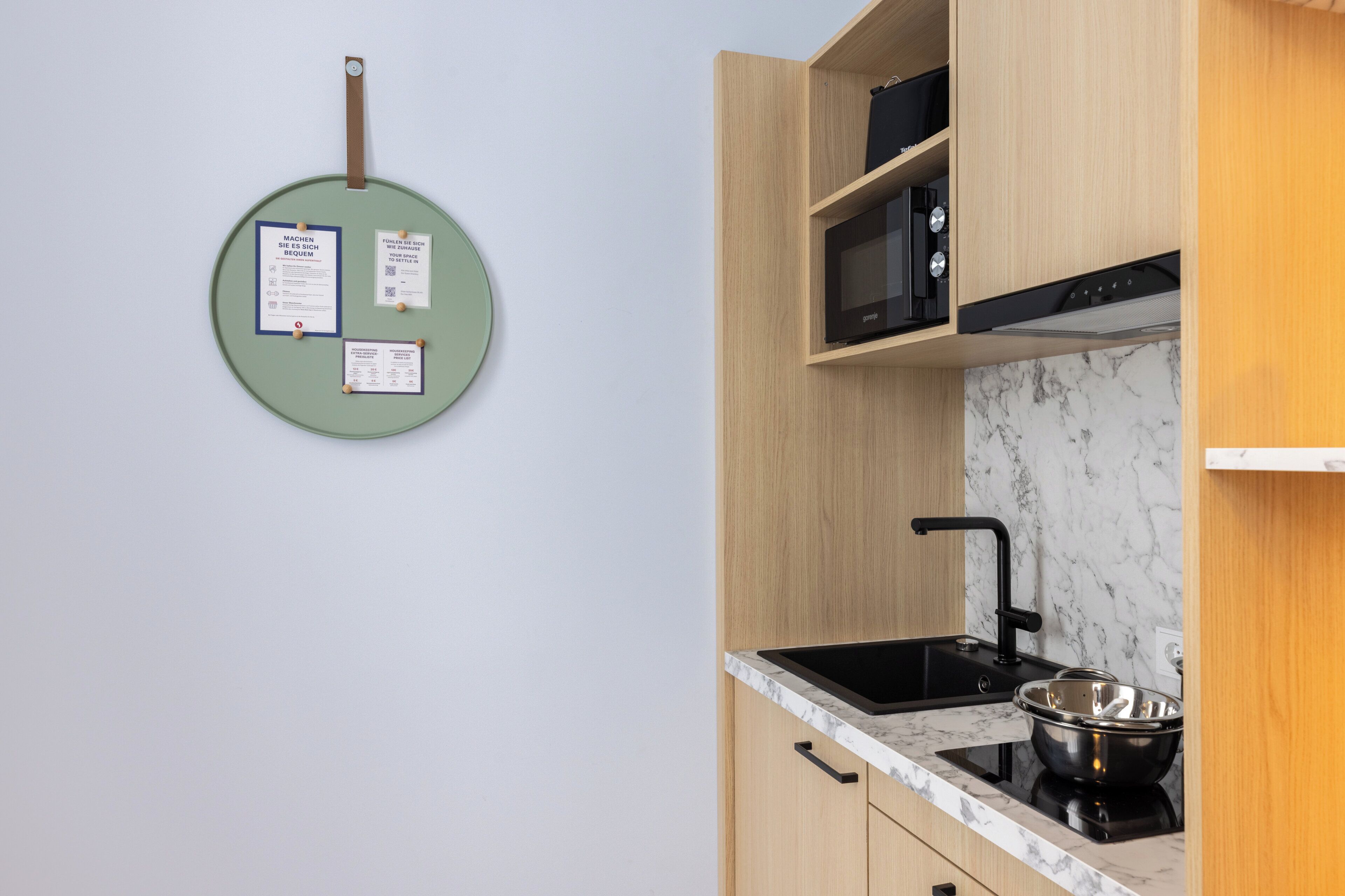 A kitchen with a black induction cooktop, a sink, and wooden cabinets.