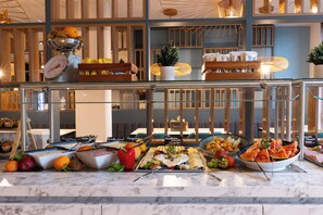 A buffet with various food options and a scale for weighing items. - Candlewood Suites Berlin Airport by IHG (Schoenefeld)