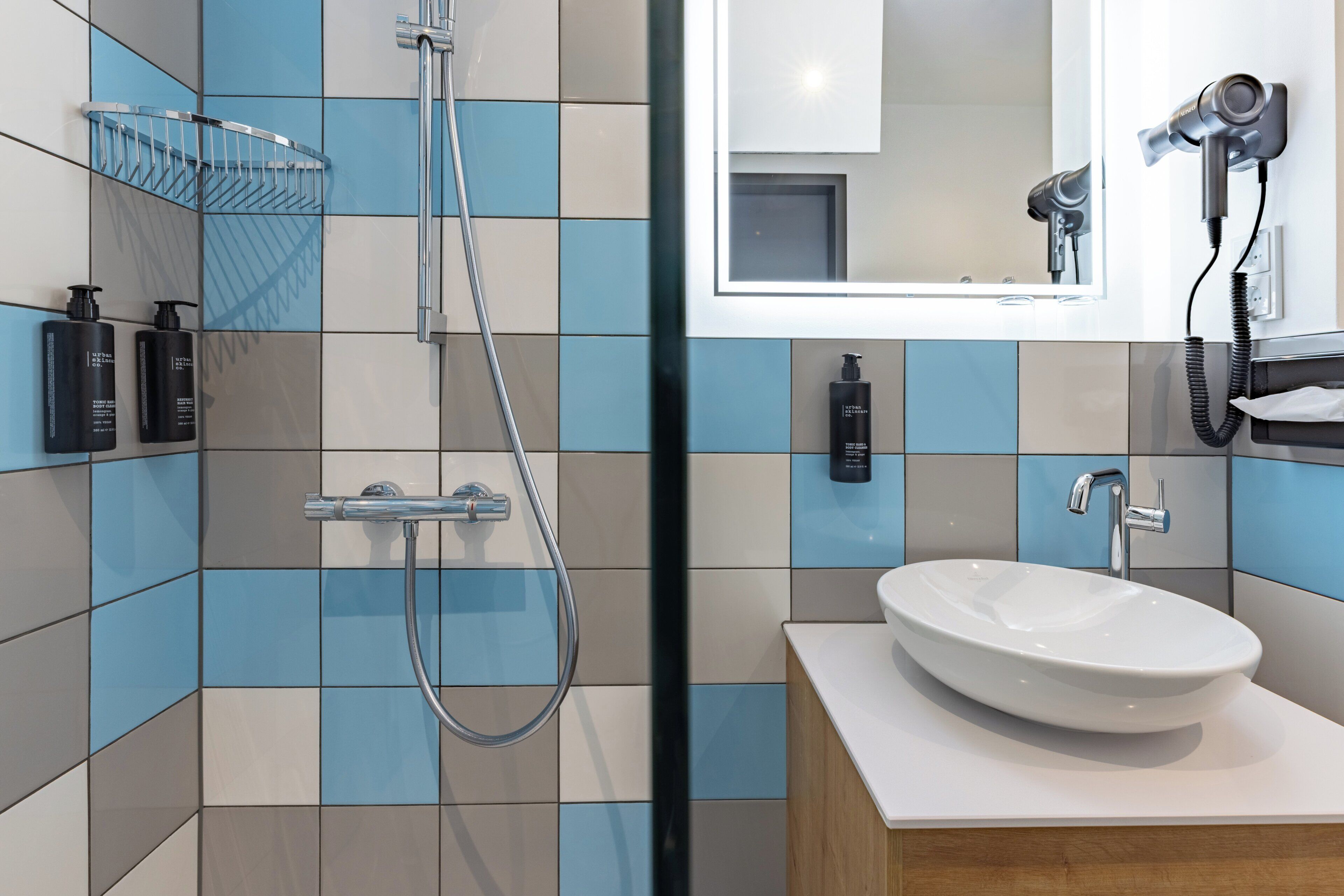 A bathroom with a shower, a sink, a mirror, and a hairdryer.