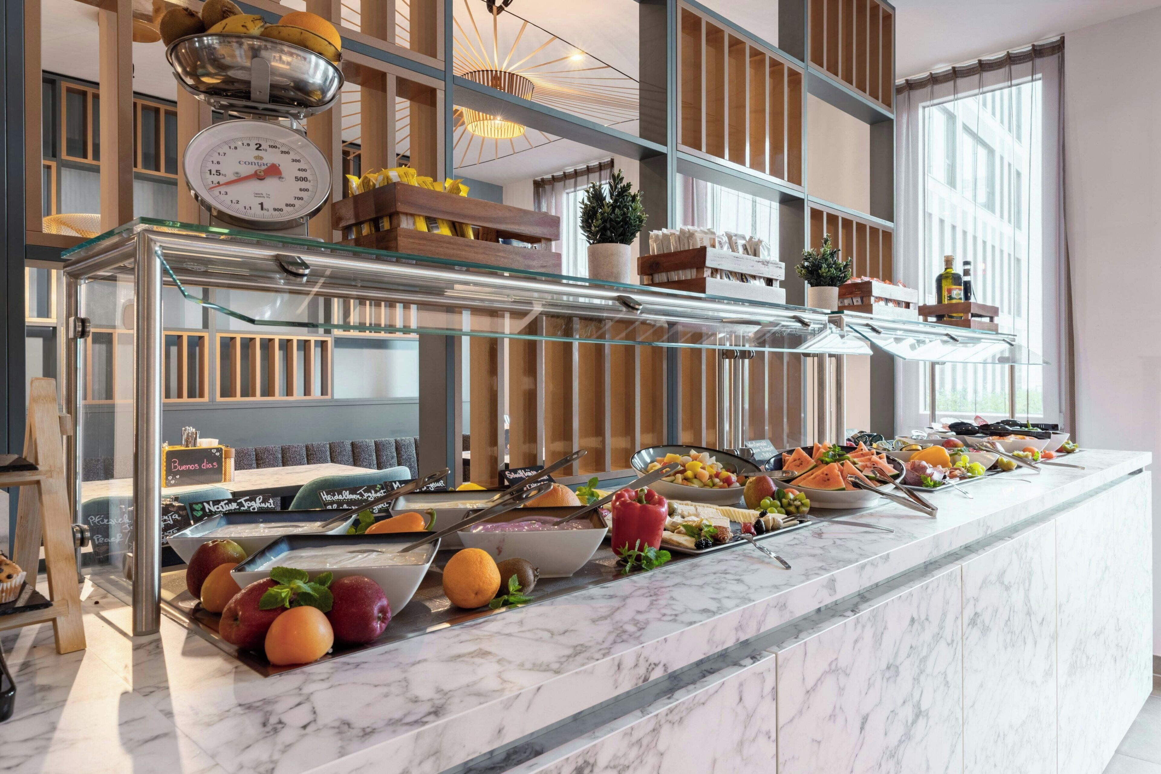 A buffet setup with various food items and a weighing scale.