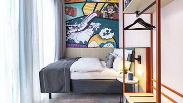 A modern hotel room with a bed, a bedside table with a lamp, a wall-mounted shelf, and a large comic-style mural.