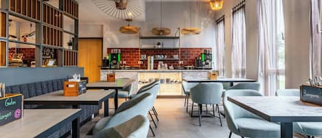 Un restaurant moderne avec un intérieur élégant, des tables hautes, des sièges confortables, une cuisine ouverte et de grandes fenêtres.