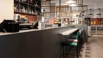 A bar area with a counter, stools, and a variety of bottles.