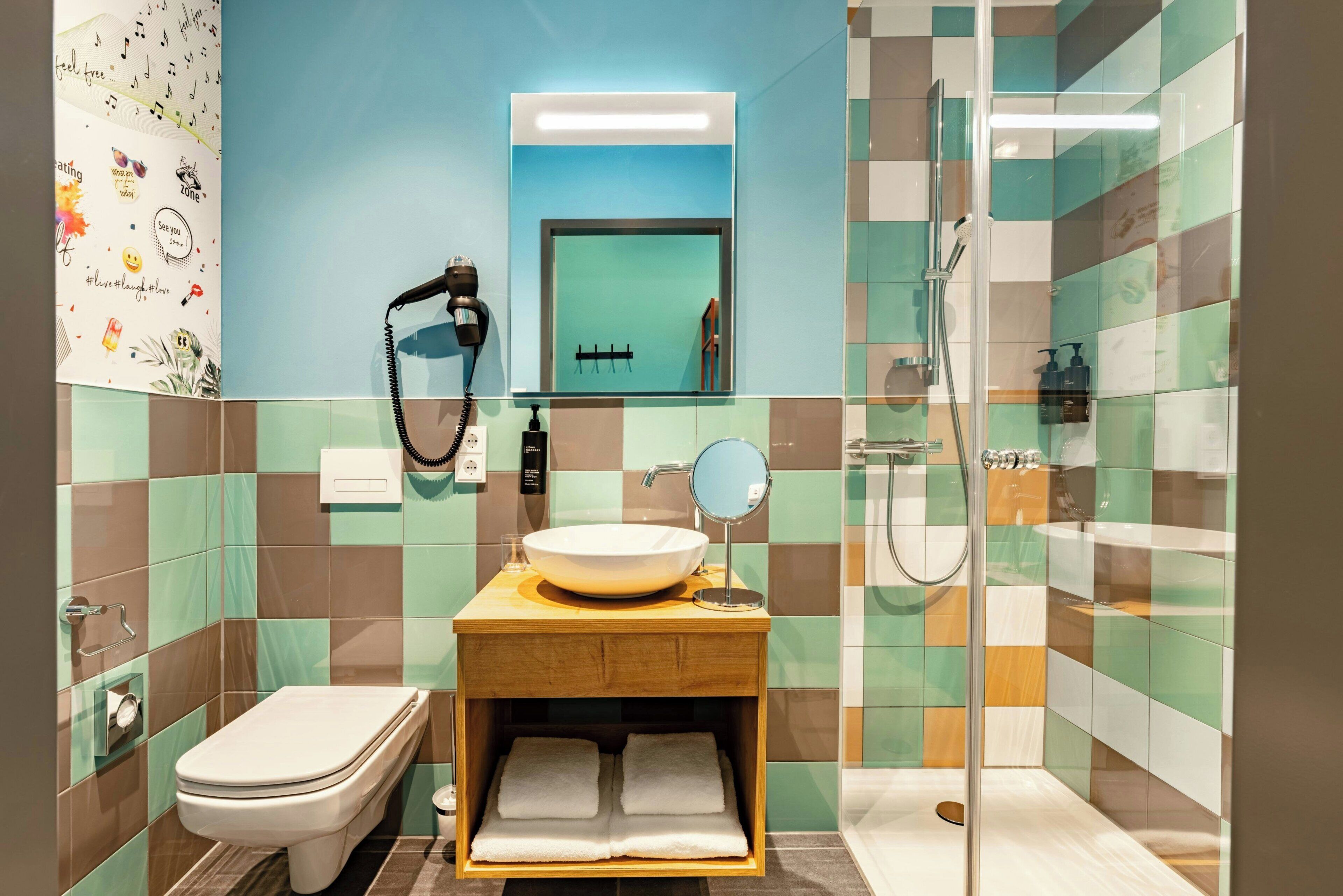 A bathroom with a toilet, sink, mirror, and shower.