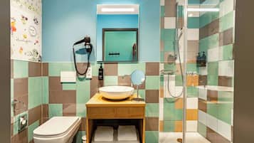 A bathroom with a toilet, sink, mirror, and shower.