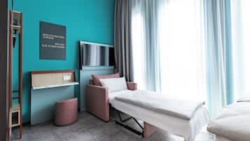 A modern bedroom with a bed, a TV, a shelf, and a motivational quote on the wall.