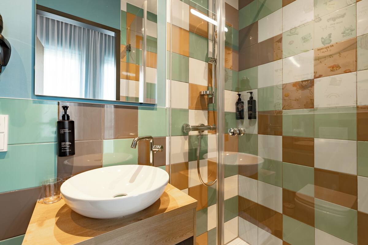 A bathroom with a glass-enclosed shower, a white sink, and a mirror above it.