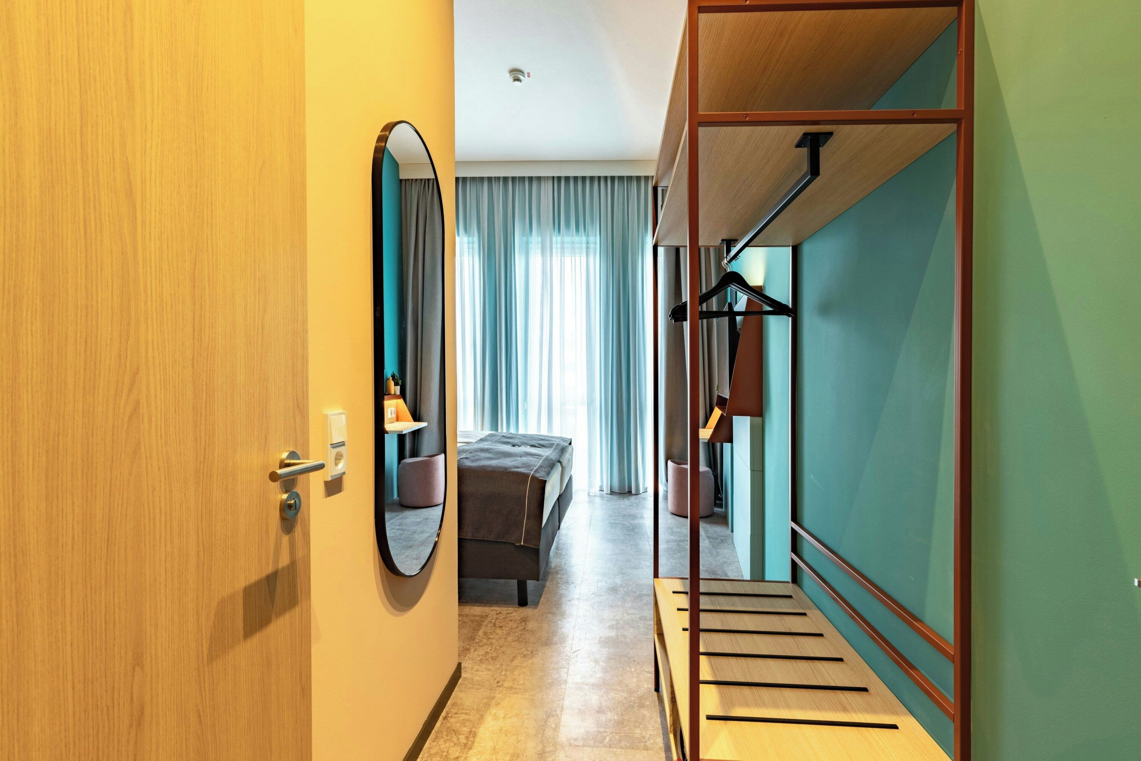 Une chambre d’hôtel avec un lit, un miroir, une armoire et un escalier.