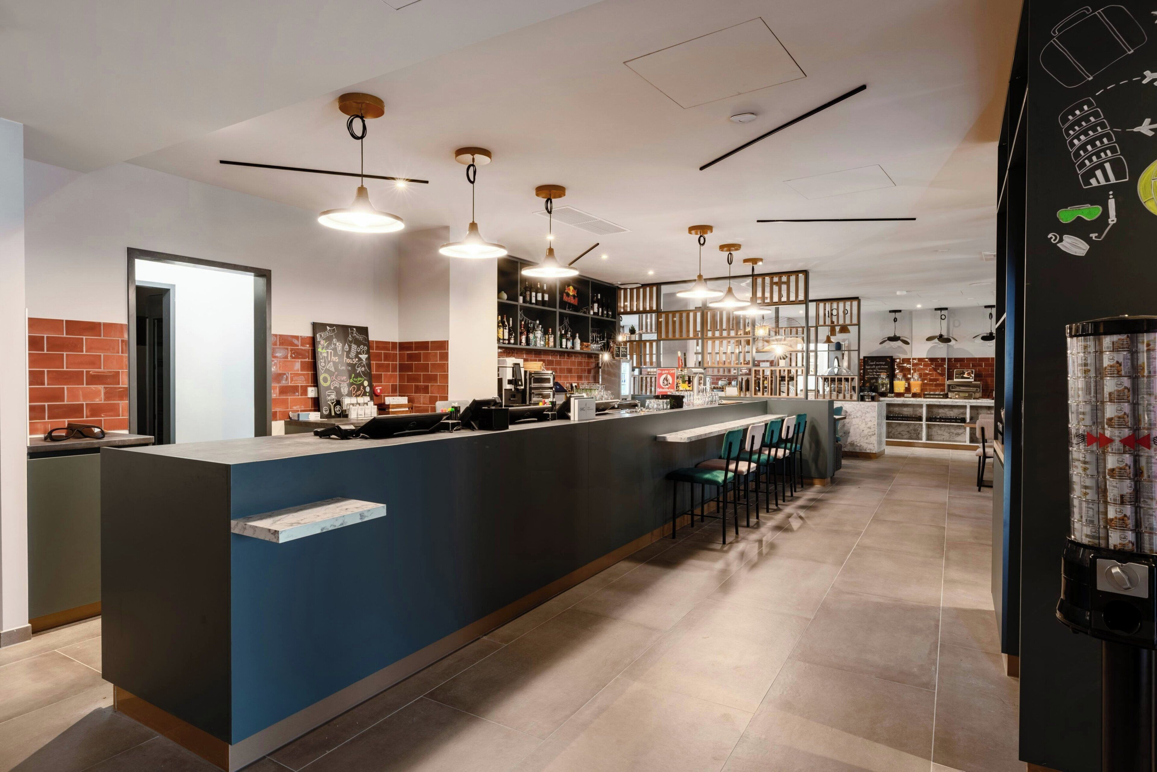 A modern bar area with a long counter, bar stools, and a variety of bottles and glasses.