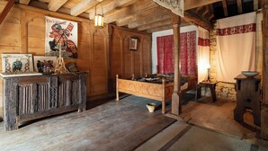A rustic wooden room with a bed, a dresser, and a tapestry on the wall. - The Manoir de Damigny in Normandy near the landing beaches and Bayeux (SAINT MARTIN DES ENTREES)