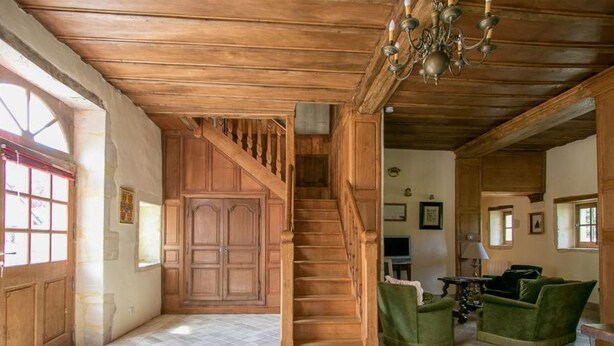 A spacious living area with a wooden staircase, green upholstered chairs, and a chandelier. - The Manoir de Damigny in Normandy near the landing beaches and Bayeux (SAINT MARTIN DES ENTREES)