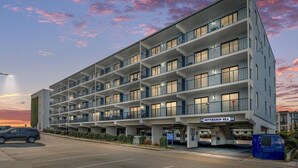 A multi-story hotel with balconies, a parking area, and a sign reading "Sovereign Sea". - Ocean Block, Ocean View 2 Bedroom Condo on 37th St. Sovereign Sea. Next to Coconuts Beach Bar and many other great places! Sovereign Sea #106 (Ocean City)