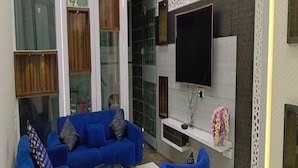Uma sala de estar moderna com um sofá azul, uma mesa de centro e uma TV na parede.