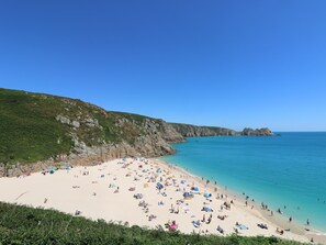 A beach with a rocky cliff and a clear blue sea. - Mermaid Cottage (Penzance)