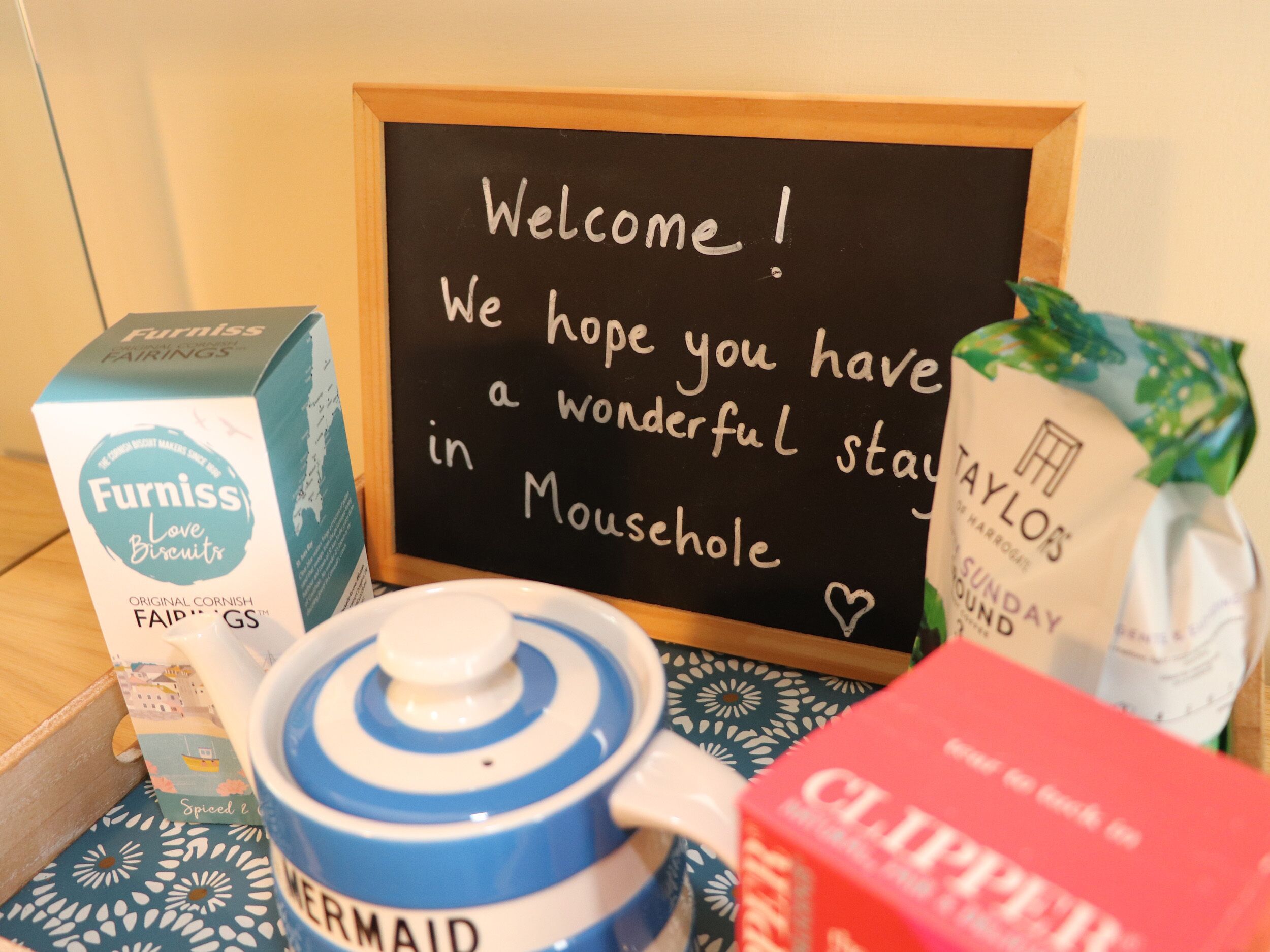 A welcome sign, a box of Furniss Love Biscuits, a blue and white pot labeled "MERMAID", and a red box of Clorox wipes.