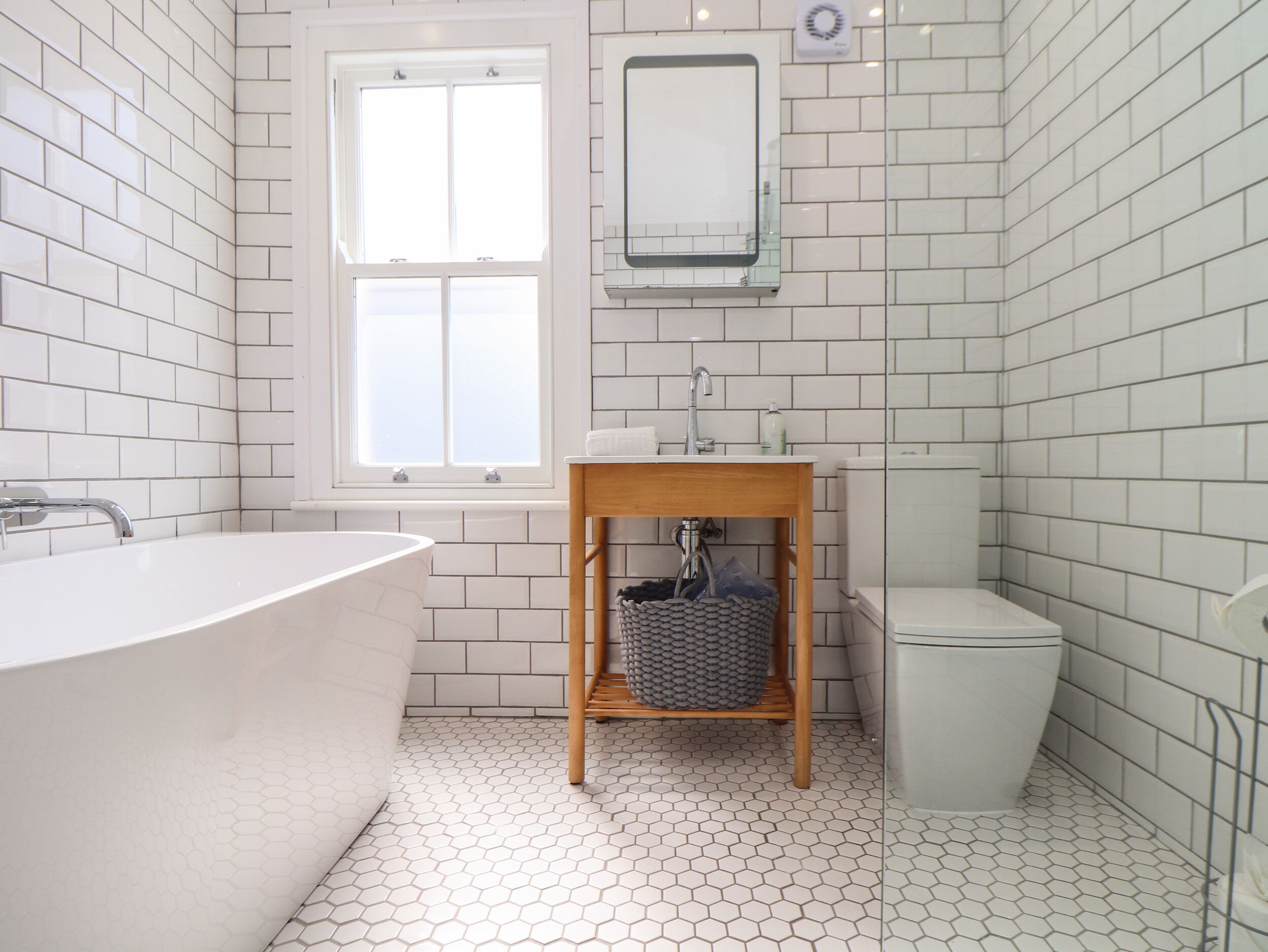 Un baño con una bañera blanca, un tocador de madera con un lavabo y un inodoro.