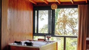 A wooden cabin with a large window, a bathtub, and two wine glasses on the windowsill. - Yörükali Tesisleri (Adalar)