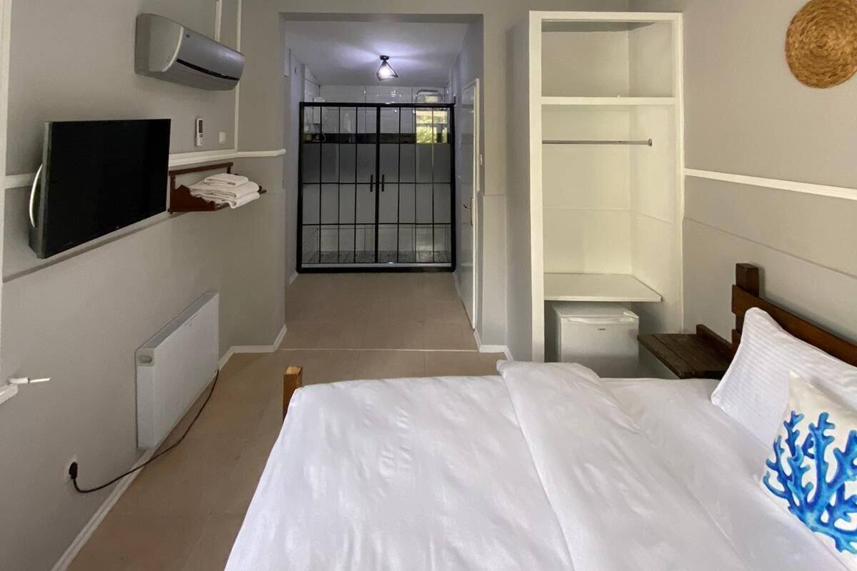 A bedroom with a bed, a TV, a wardrobe, and a bathroom visible through an open door.