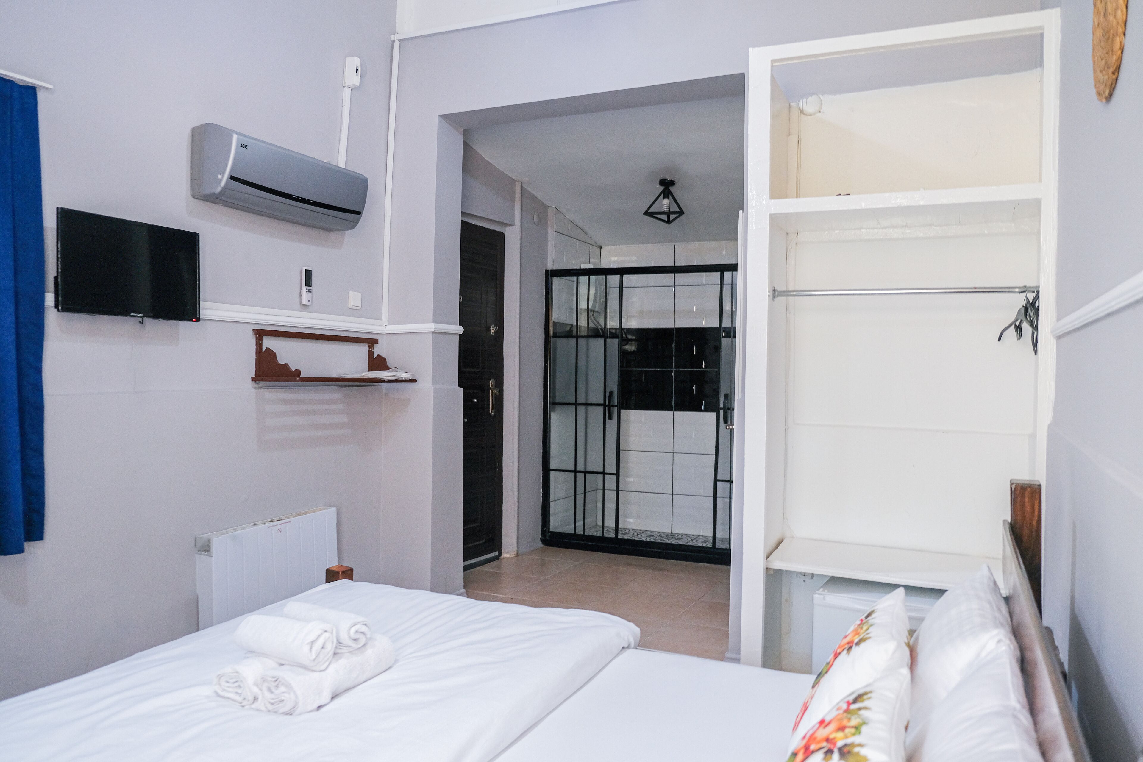 Une chambre d’hôtel équipée d’un lit, d’une télévision, d’un climatiseur, d’une douche et d’un placard.