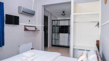 Une chambre d’hôtel équipée d’un lit, d’une télévision, d’un climatiseur, d’une douche et d’un placard.