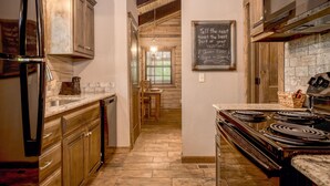 A kitchen with wooden cabinets, a stove, and a chalkboard with a message.