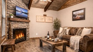 A cozy living room with a stone fireplace, a leather sofa, and a wooden coffee table.