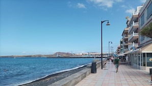A seaside promenade with a tiled walkway, a sea wall, and buildings with balconies. - Apartamento Sol y Mar (Arona)