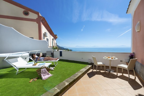 A terrace with a view of the sea, a small lawn, and outdoor furniture. - Casa Terry - Lovely Apartment With sea View (Praiano)