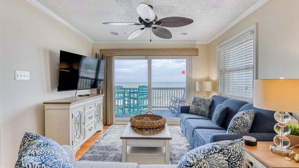 A living room with a television, a ceiling fan, a sofa, a coffee table, and a view of the ocean through a balcony. - Sea Master 315 - Three Bedroom, Three Bathroom, Oceanfront Condo (Garden City Beach)